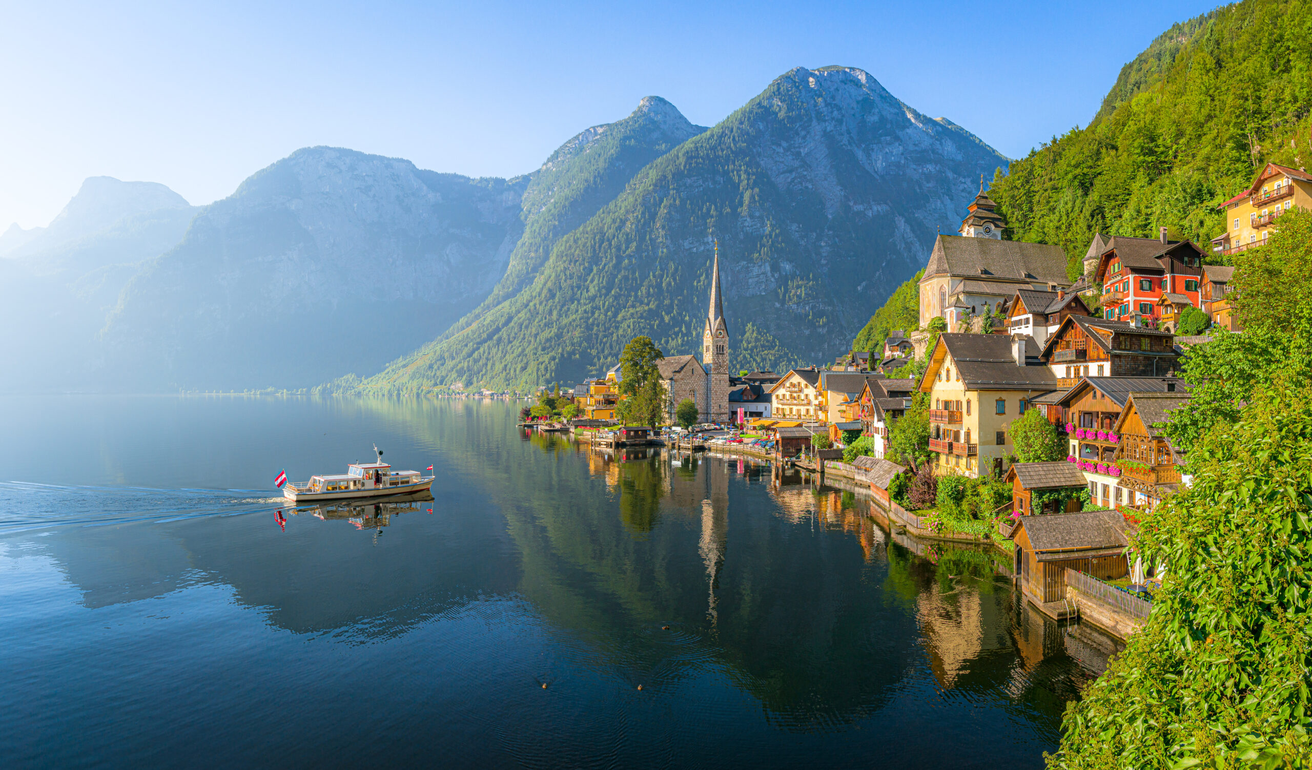 Panoramic view of idyllic old lake town in the Alps with famous old town with tourist ship in scenic golden morning light on a beautiful sunny day at sunrise in summer